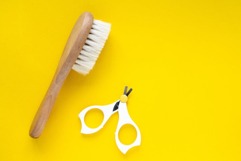 Close-up of a wooden brush and scissors on a vibrant yellow background. Perfect for lifestyle or grooming themes.